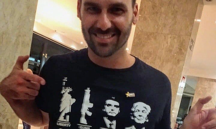 Na imagem, ele usa camiseta em que a sigla da comunidade foi substituída por Liberdade, Armas, Bolsonaro e Trump.