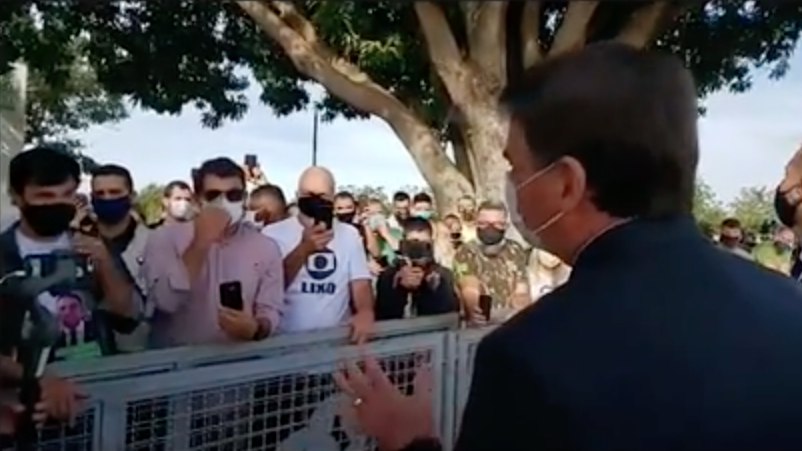 um homem de costas conversa com um grupo de homens frente a frente