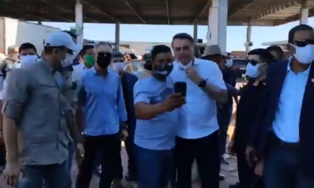 Contra recomendações e com abraços, o presidente Jair Bolsonaro provoca aglomeração em posto de gasolina em Cristalina, Goiás. (Foto: reprodução)