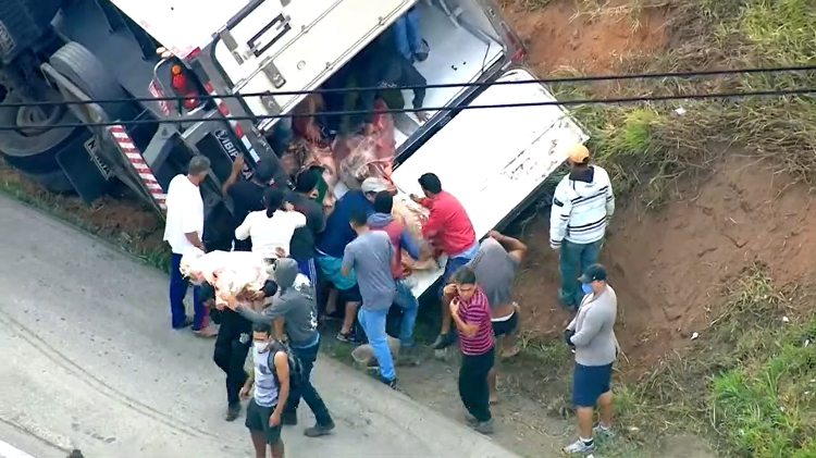 Um caminhão frigorífico que carregava carne tombou hoje em São Paulo e teve a carga saqueada. A rodovia ficou bloqueada. (Foto: TV Globo)