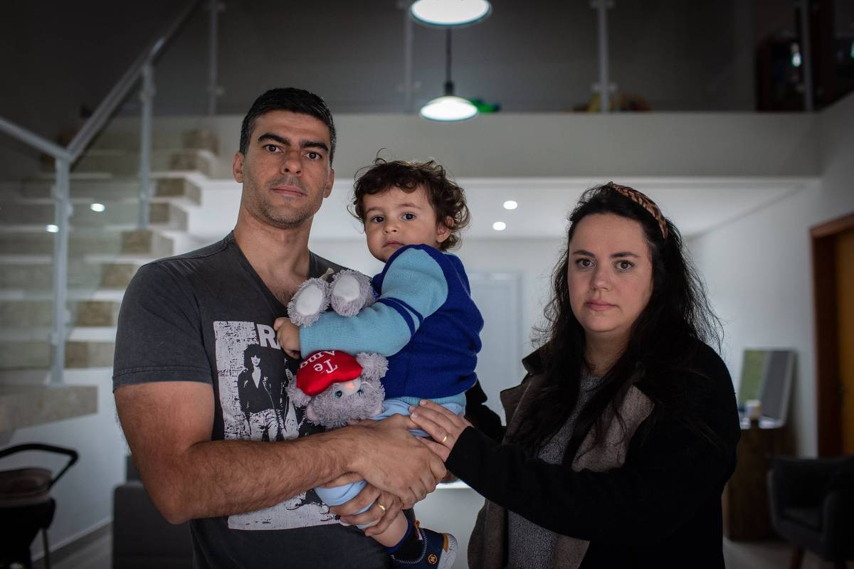 Miguel, de um ano e oito meses, com sua mãe Caroline Cunha e seu pai Adriano Jorge de Oliveira, é uma das crianças com a síndrome (Foto: Bruno Santos/Folhapress)