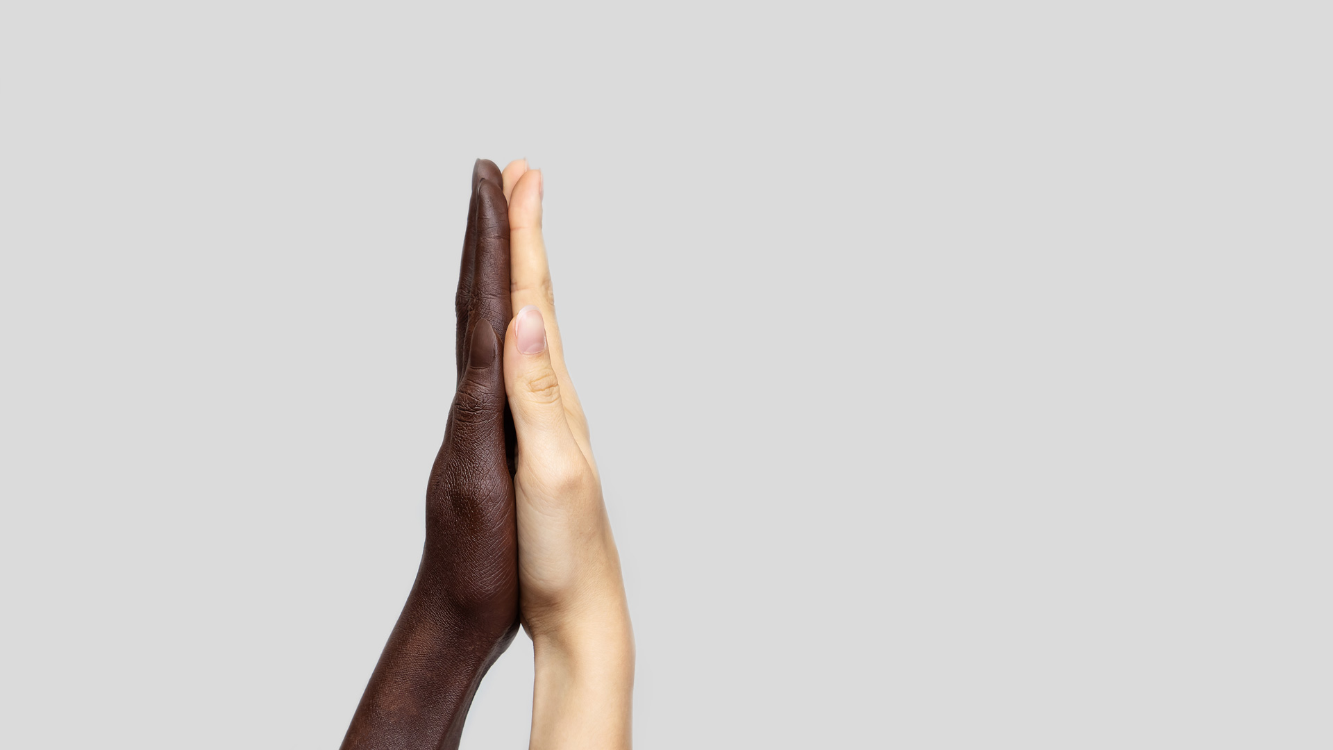 Mãos negra e branca unidas pelas palmas (Foto: Natalia Riabchenko/Shutterstock)