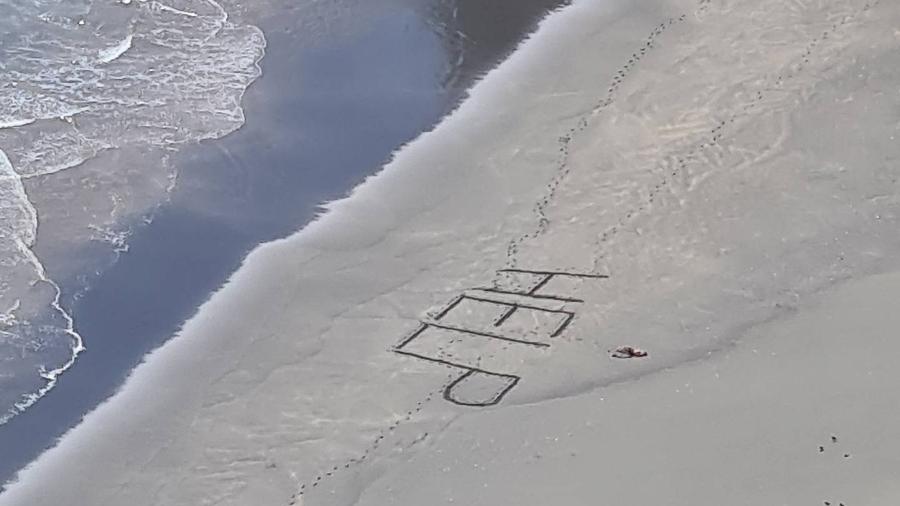 Surfista ferido é resgatado de praia remota ao escrever 'socorro' na areia