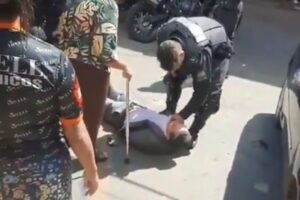 Advogado caído enquanto PM se abaixa sobre o corpo dele
