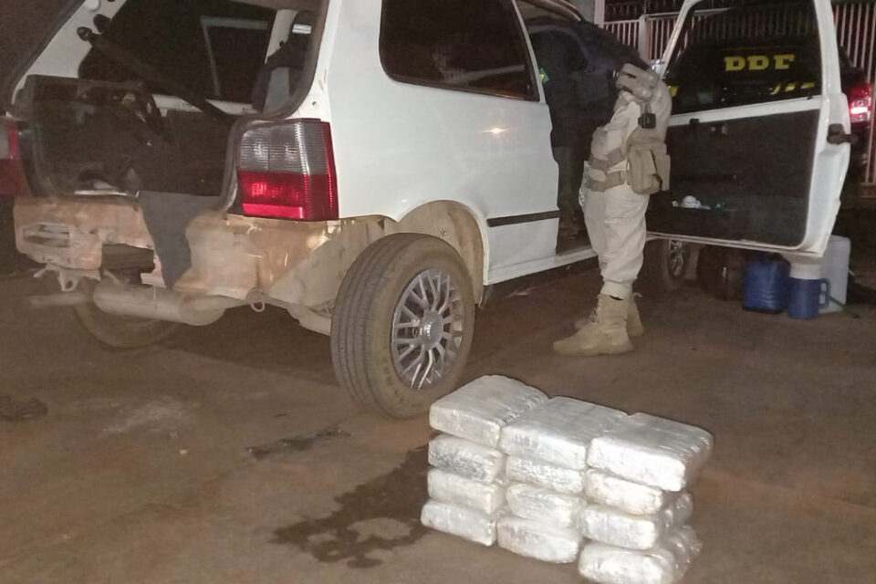 Foto mostra drogas ao lado de veículo com portas abertas, sendo vistoriado por agentes rodoviários - Casal é preso na frente do filho com 30 quilos de maconha na BR-060, em Acreúna