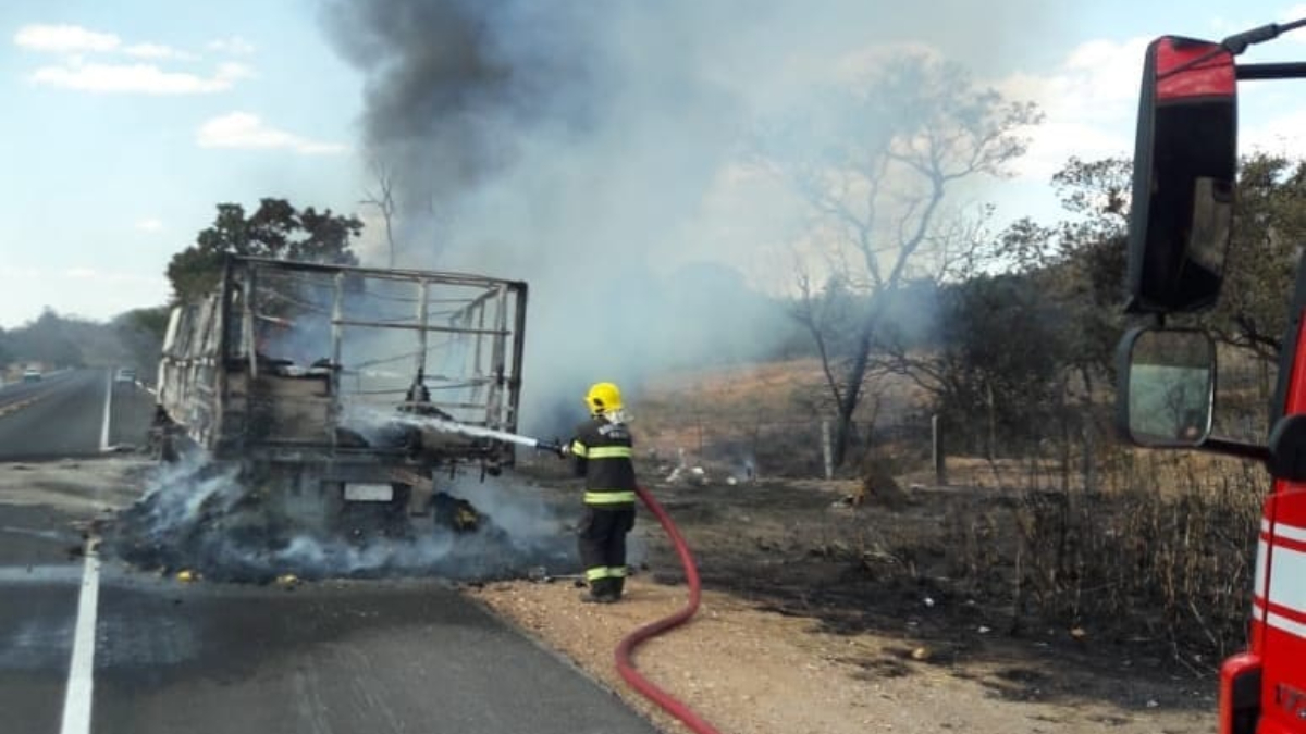 Bombeiro com mangueira de água tenta conter chamas em caminhão, que já está completamente carbonizado. Foto ilustra chamada: Incêndio destrói caminhão e carga após pane no motor na BR-414, em Niquelândia