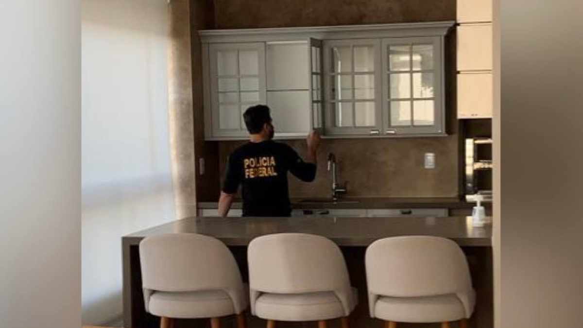 Agente federal realiza vistoria em cozinha de casa. Foto ilustra a chamada: Polícia Federal investiga ação de hackers em Goiânia e outras 5 cidades do Brasil