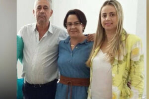 O pai à esquerda, a mãe no meio e a filha na outra extremidade posam para a foto. As duas mulheres sorriem e o homem se mantém sério. Foto ilustra a chamada: Família vítima de triplo homicídio no Paraná é enterrada em Pires do Rio