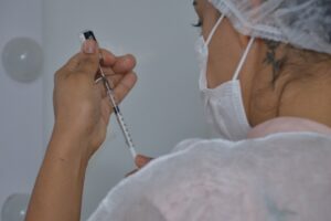 Mutirão de vacina - Mulher com ampola e seringa de imunizante contra Covid-19