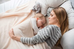 Mãe de primeira viagem colocando seu filho para domir - Privação de sono de novas mães pode acelerar o envelhecimento, diz estudo