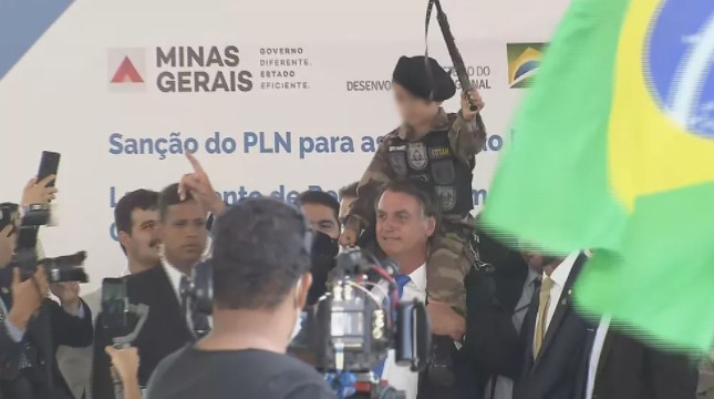 Bolsonaro posa para fotos com criança fardada e com arma de brinquedo na mão, em evento de BH — Foto: TV Globo
