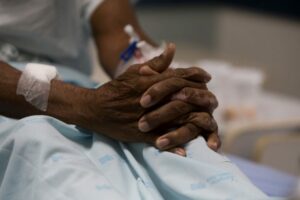 Mulher negra aguarda medicamento sentada em uma cama de hospital