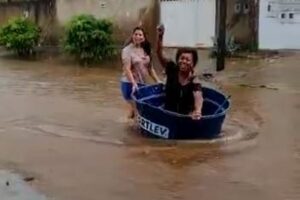 Moradora usa caixa d'água como barco em rua alagada de Goiânia
