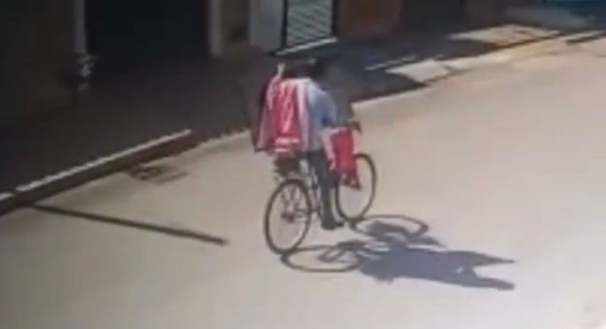 Câmera flagrou o homem fugindo de bicicleta e segurando a televisão. (Foto: Captura)