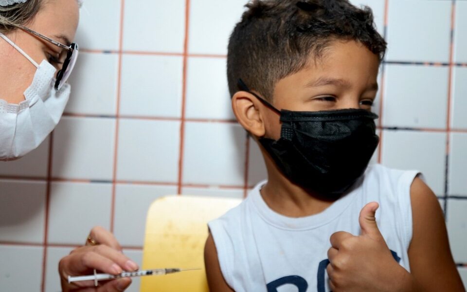 Criança faz o gesto de positivo ao receber vacina em Aparecida de Goiânia (Mais de 39% das crianças se vacinaram contra a Covid-19 nas escolas em Aparecida)