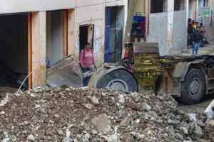 Equipes trabalham para retirar escombros de prédio atingido pelo deslizamento (Foto: Said Velesquez / AFP)