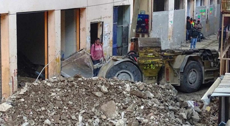 Equipes trabalham para retirar escombros de prédio atingido pelo deslizamento (Foto: Said Velesquez / AFP)
